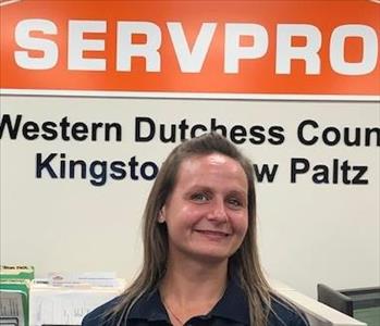 A photo of a smiling female SERVPRO employee with light brown hair in a black SERVPRO shirt