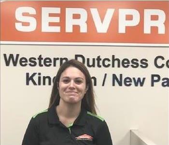 A photo of a smiling female SERVPRO employee with long brown hair in a black SERVPRO shirt.