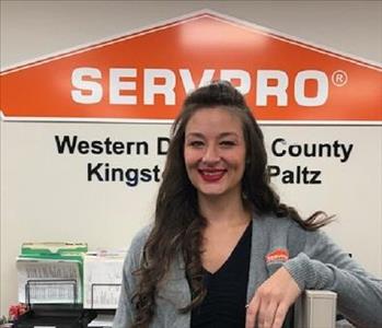 A photo of a smiling female SERVPRO employee with long brown hair in a black SERVPRO shirt