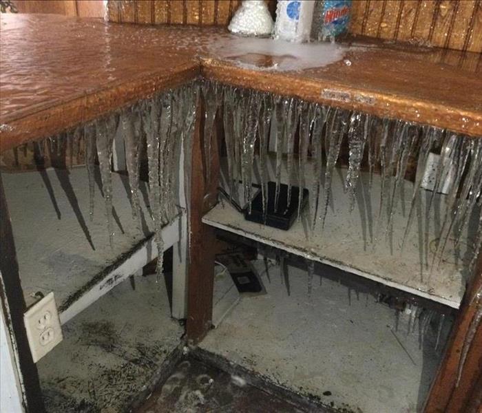 Icicles inside of a kitchen from a frozen pipe