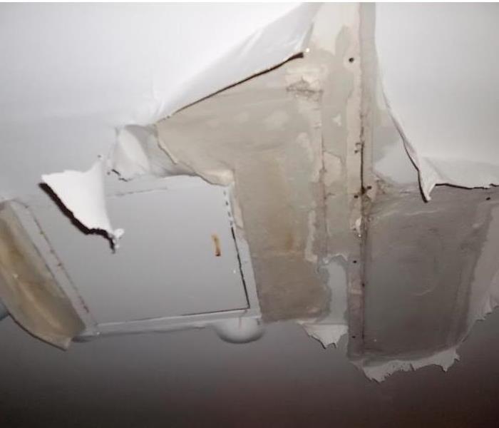 White paint and drywall peeling and coming off of a ceiling