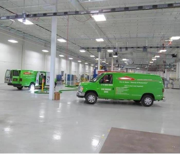 2 SERVPRO green vans inside a sparkling white warehouse